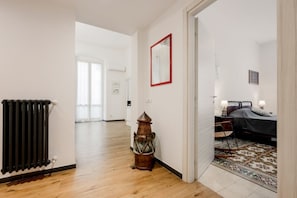 Un couloir avec un radiateur, une lanterne et un lit recouvert d’un tapis à motifs.