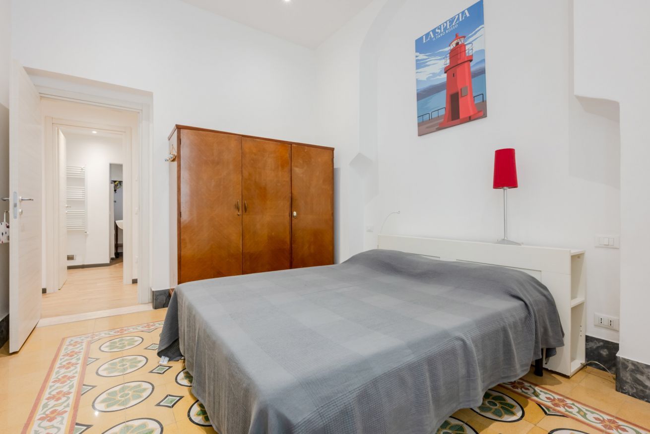 A bedroom with a bed, wardrobe, and a poster on the wall.