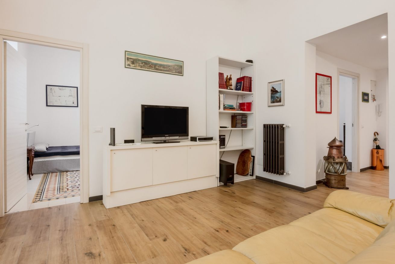 Ein Wohnzimmer mit einer Couch, einem Fernseher, einer weißen Unterhaltungseinheit und einem Bücherregal.