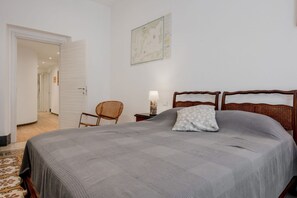 Una camera da letto con un letto, una sedia, un comodino, una lampada e una mappa appesa al muro.