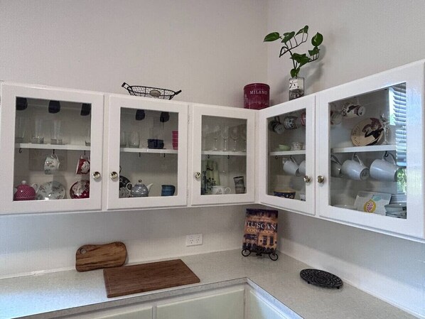 A kitchen with white cabinets, a wooden cutting board, and a small cart.