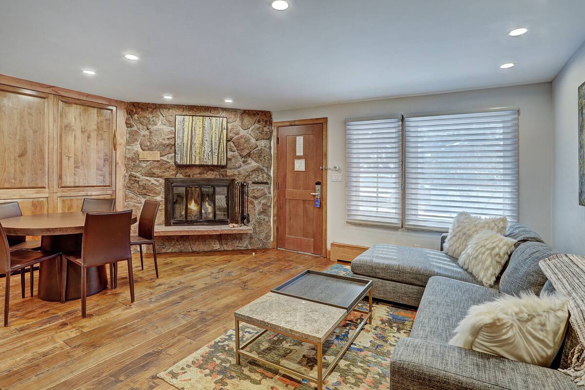 A living room with a stone wall, fireplace, dining table, and sofa.