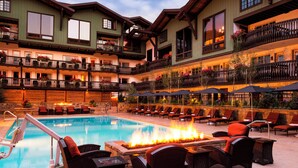 Un hotel con zona de piscina, mobiliario exterior y una chimenea.