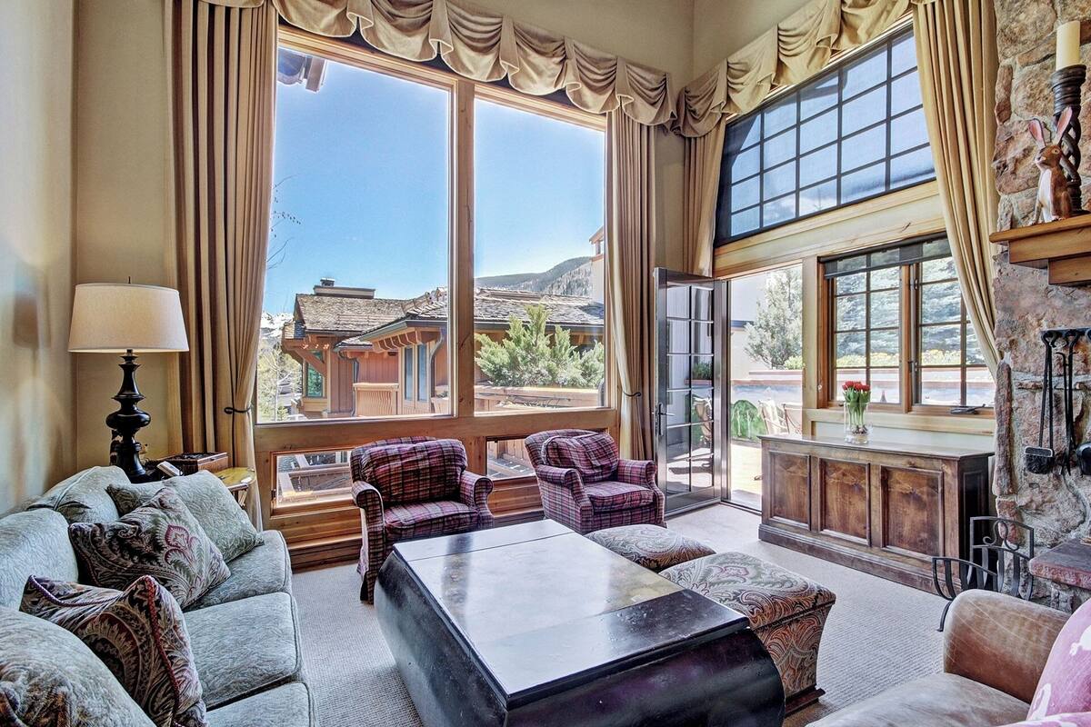 A spacious living room with large windows, a fireplace, and a view of a mountain.