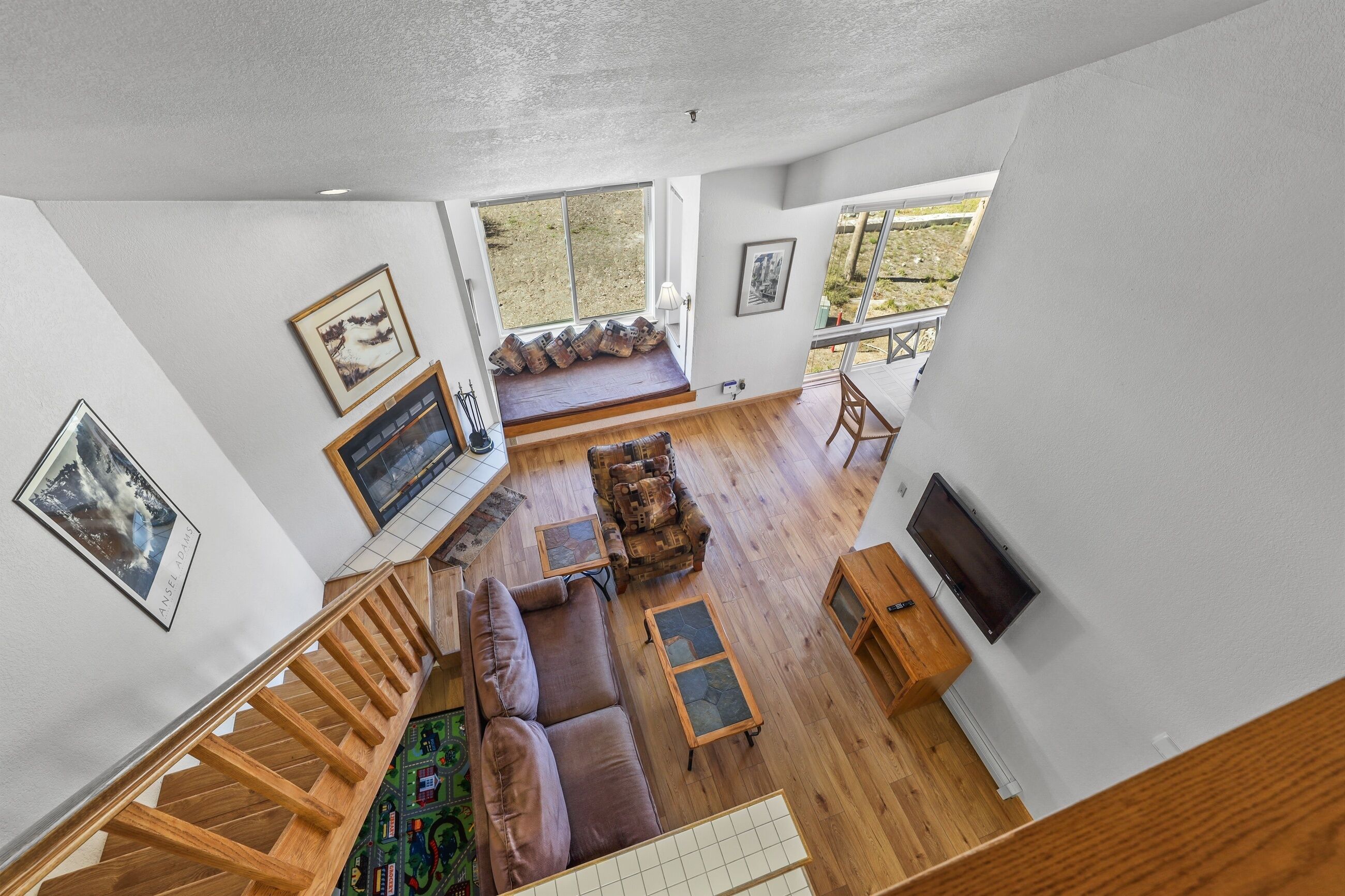 A spacious living area with a wooden staircase, a sofa, a coffee table, and a TV.