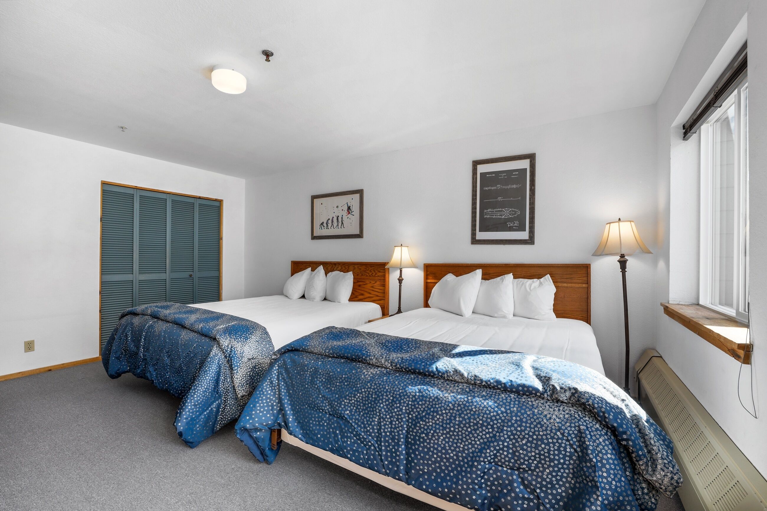 A hotel room with two beds, a window with a view, and a ceiling light.
