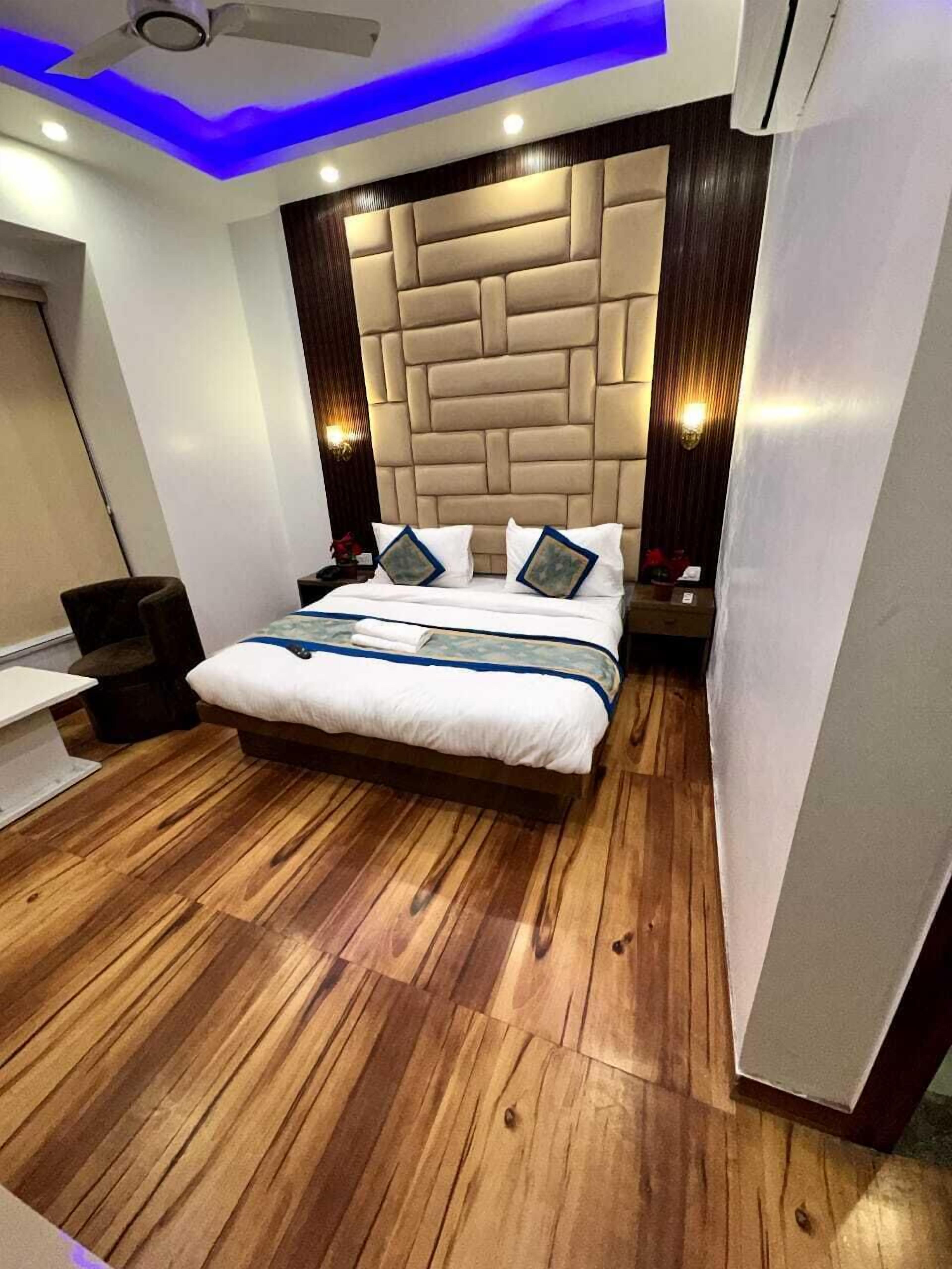 A modern bedroom with a tufted headboard, wooden flooring, and a ceiling fan.