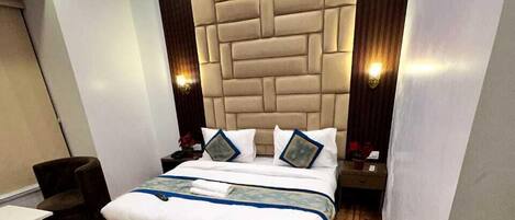 A modern bedroom with a tufted headboard, wooden flooring, and a ceiling fan.