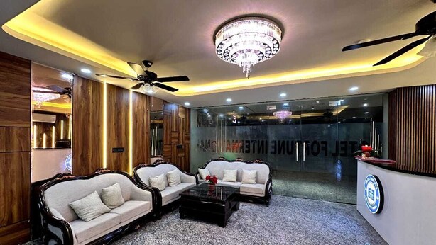 A lobby with two sofas, a coffee table, a chandelier, and a reception desk. - Sara Fortune International by Sara Hotels and Resort (Noida)