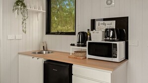A compact kitchen with a microwave, coffee maker, and a hanging plant. - Olive Sanctuary by Tiny Away (Taggerty)