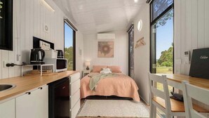 A compact bedroom with a bed, bedside table, and a view through a window. - Olive Sanctuary by Tiny Away (Taggerty)