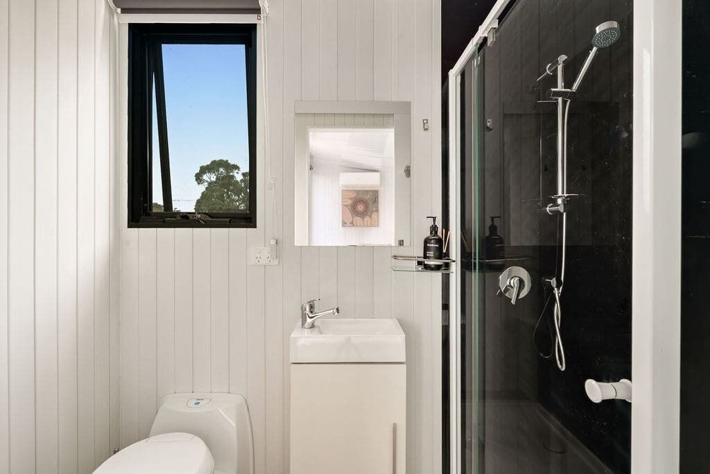 A modern bathroom with a toilet, sink, and glass-enclosed shower.