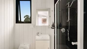 A modern bathroom with a toilet, sink, and glass-enclosed shower.