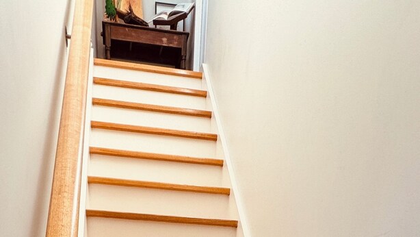 Een houten trap met witte wanden en een leuning.
