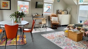 Een knus loft slaapkamer met een groot raam, een bureau, een stoel, een bed en een plant.