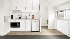 Een moderne keuken met witte kasten, een ingebouwde oven en een compacte koelkast.