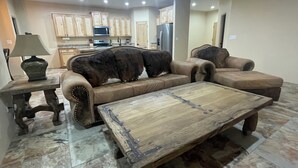 Un salon avec un canapé, une table basse et, au fond, un coin cuisine.
