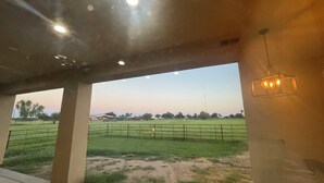 Un espace intérieur offrant une vue sur un champ verdoyant et un ciel dégagé.