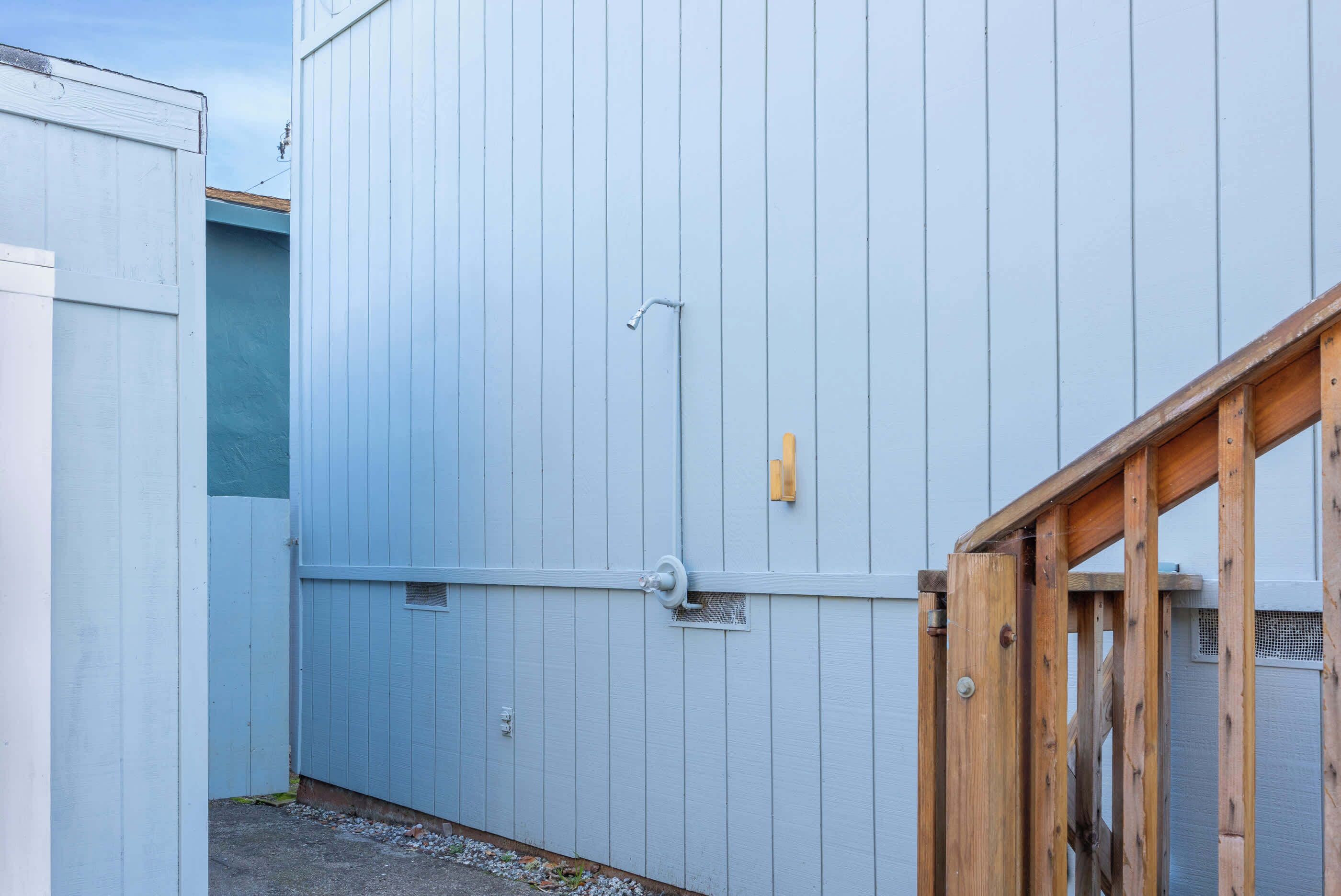 A narrow alleyway with a blue building, a wooden gate, and a metal door.