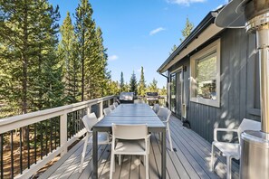 A deck with a table and chairs, surrounded by trees.