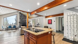 A modern kitchen with a granite countertop, wooden cabinets, and a stone fireplace. - Breckenridge Mountain Retreat | Hot Tub & Views (Breckenridge)