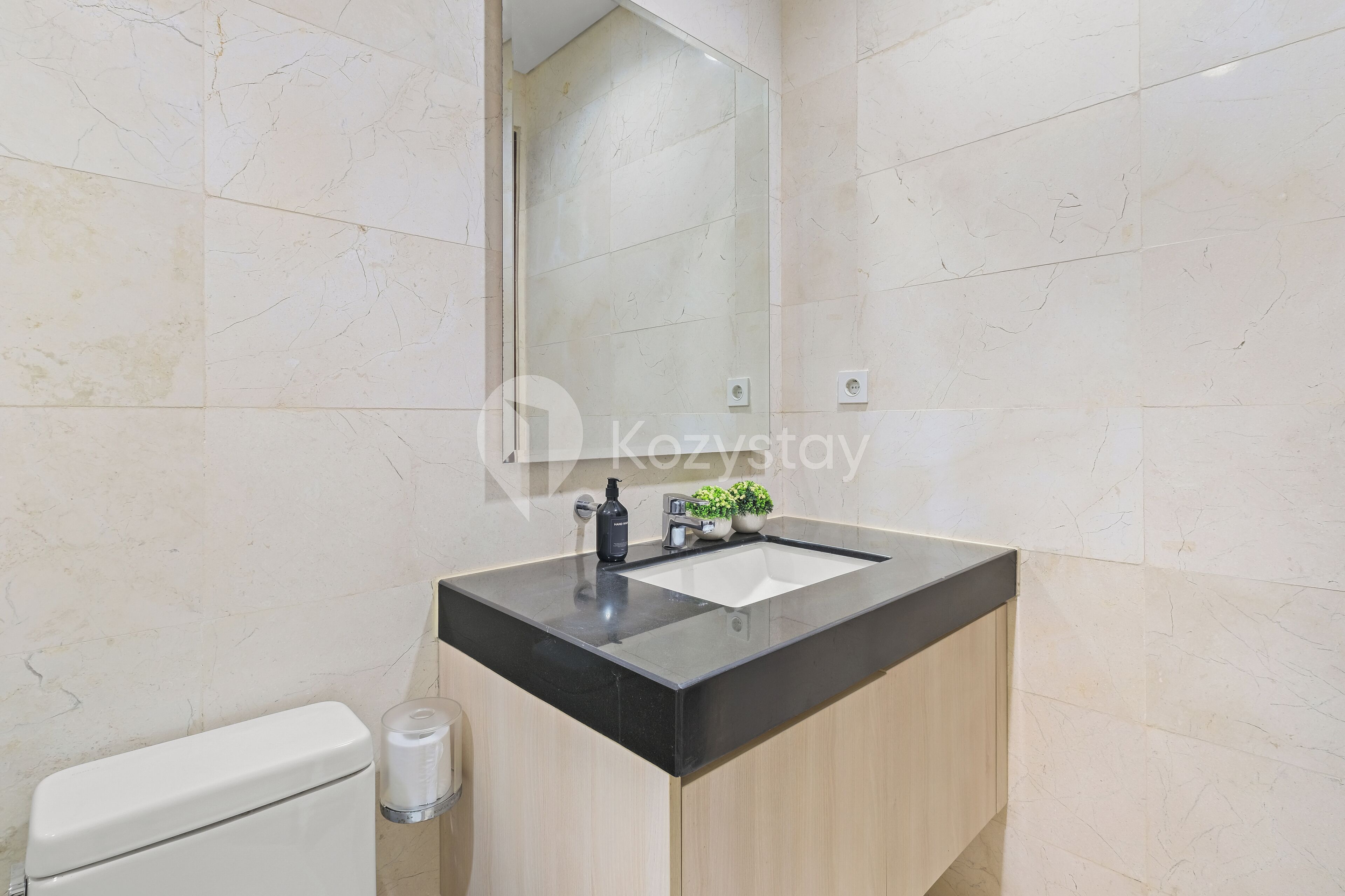 Un baño moderno con lavamanos de encimera negro, un espejo y un inodoro.