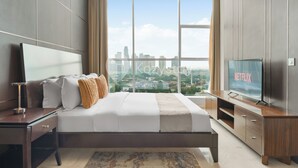 Habitación de hotel moderna con una cama grande, televisión y vista del horizonte de la ciudad.