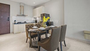 Una cocina moderna con armarios blancos, estufa integrada y un comedor con mesa dispuesta para dos.