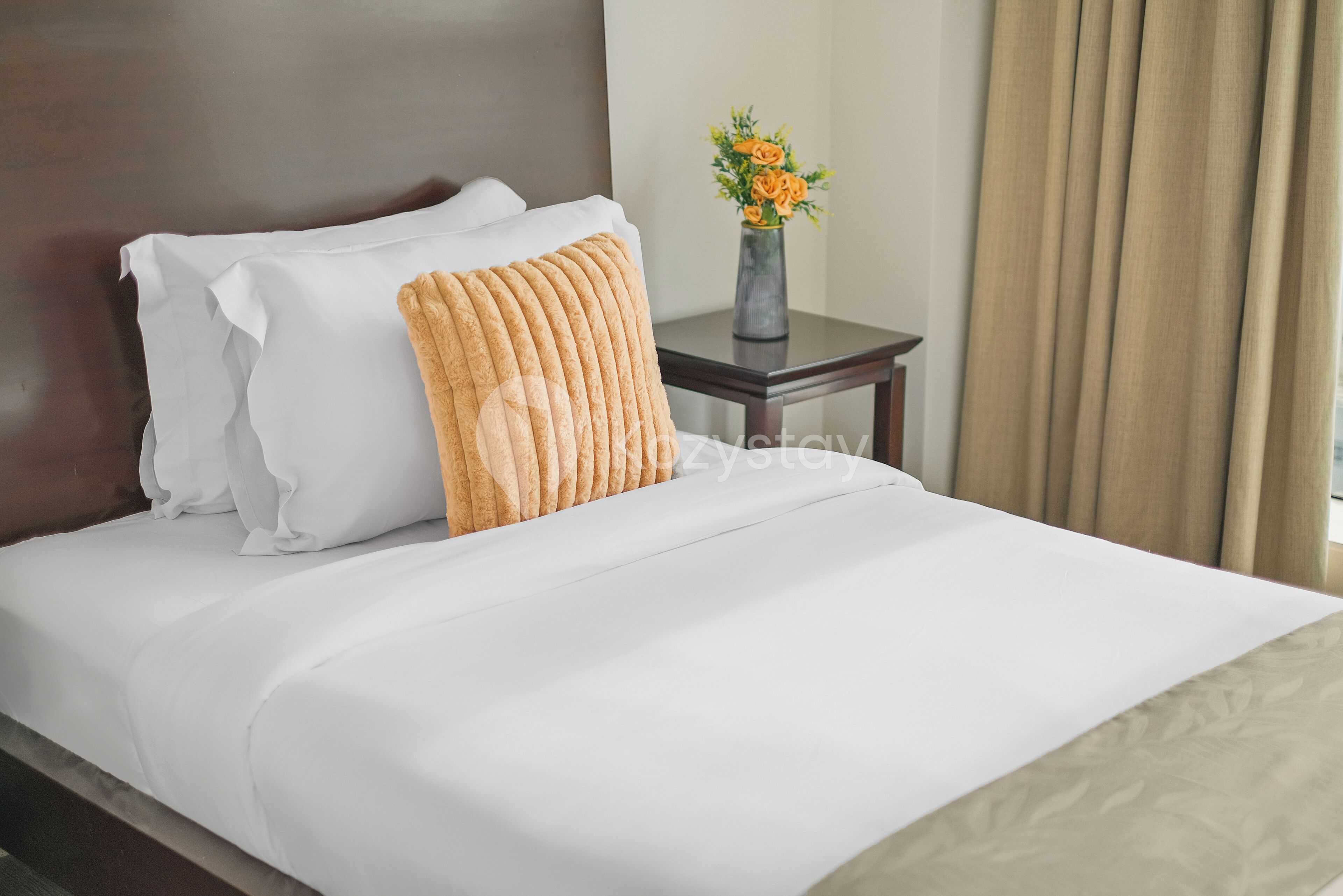 Una cama bien tendida con sábanas blancas y una única almohada decorativa.