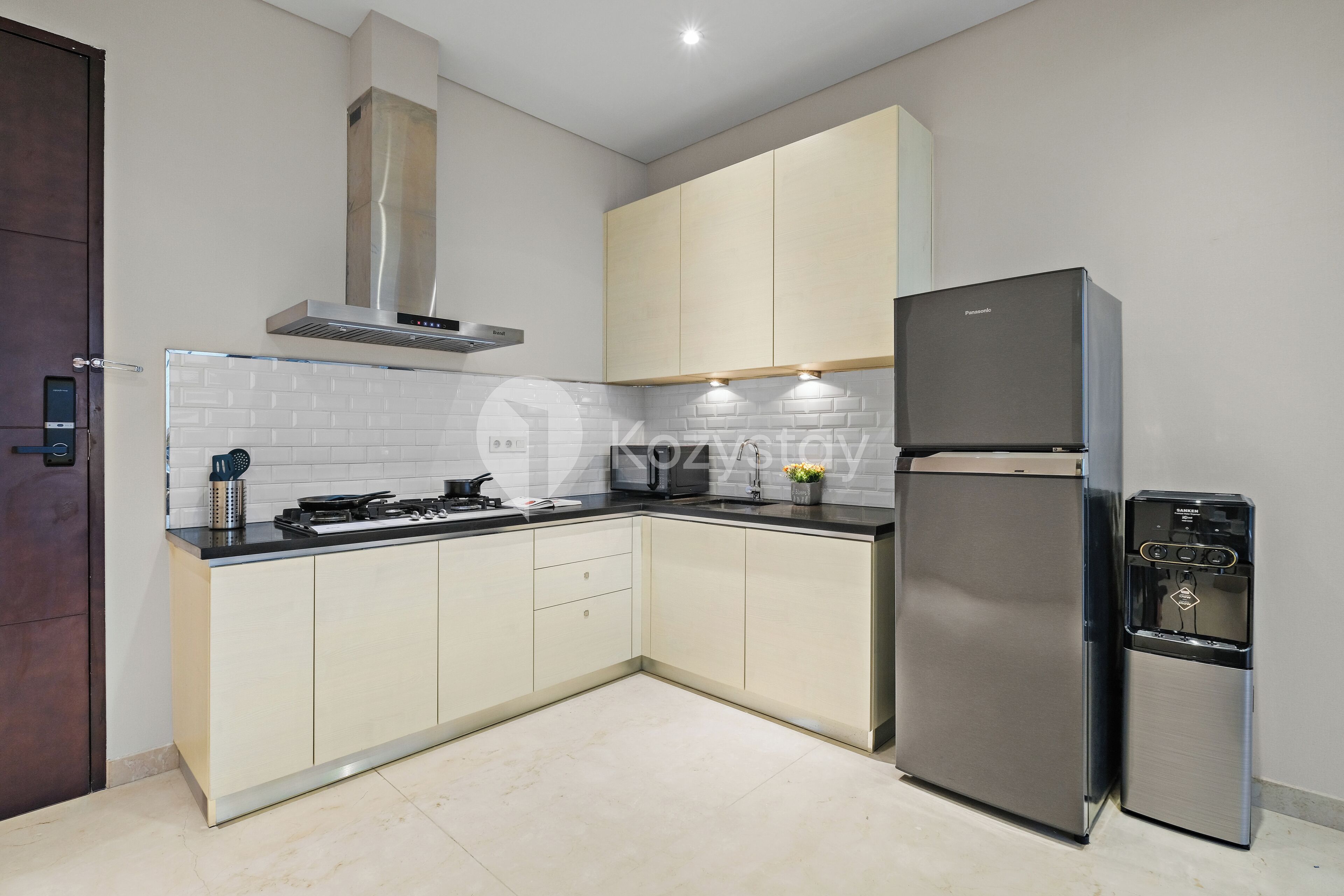 A modern kitchen with light-colored cabinets, a stainless steel refrigerator, and a built-in stove.