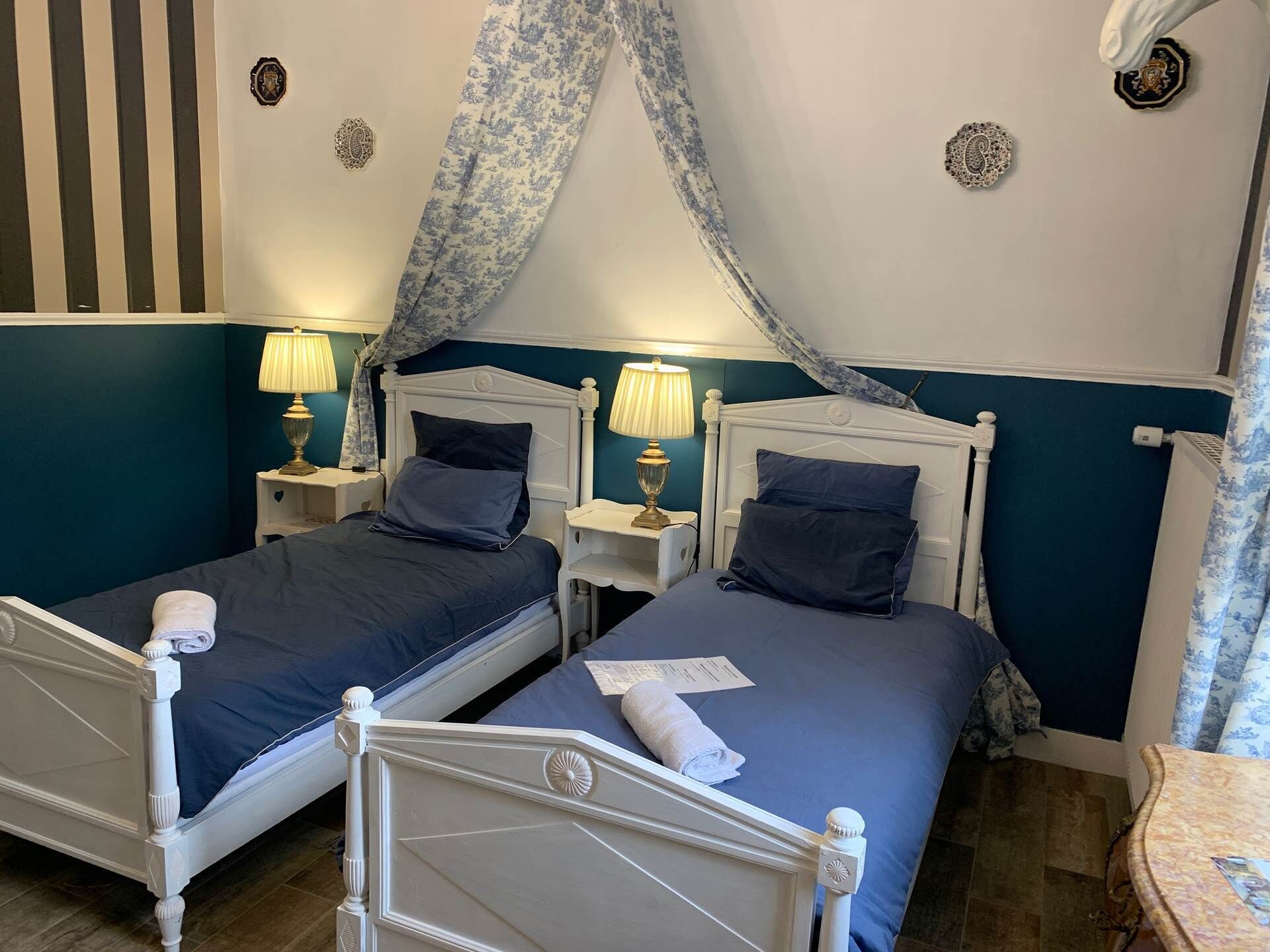 A double bed with a canopy, two bedside tables with lamps, and a small table with a chair.
