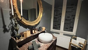 Un bagno con un vanità in marmo, uno specchio con cornice dorata, un lavandino bianco e una finestra vista.