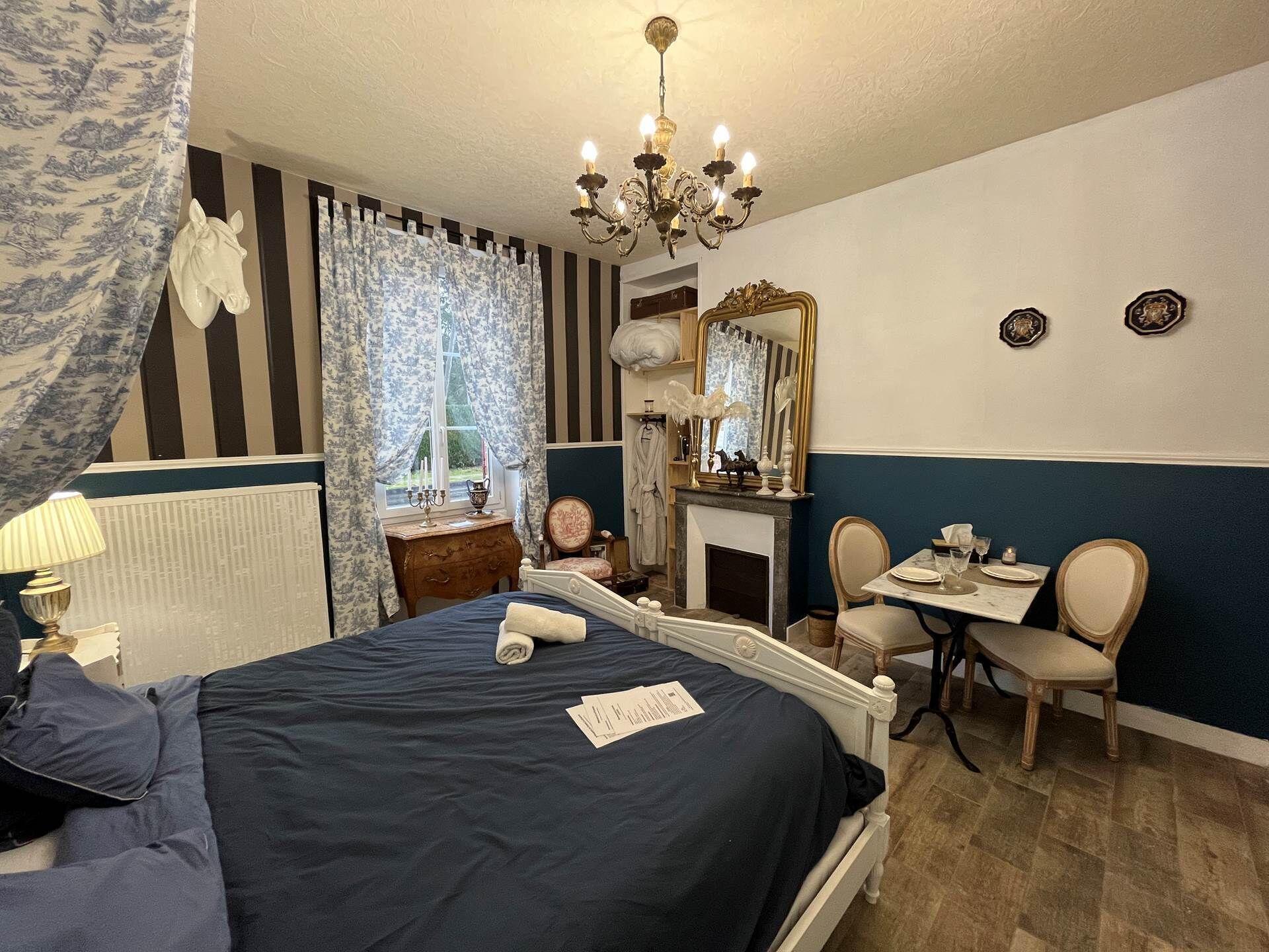 Een hotelkamer met een bed, een bureau, een stoel, een spiegel en een kroonluchter.
