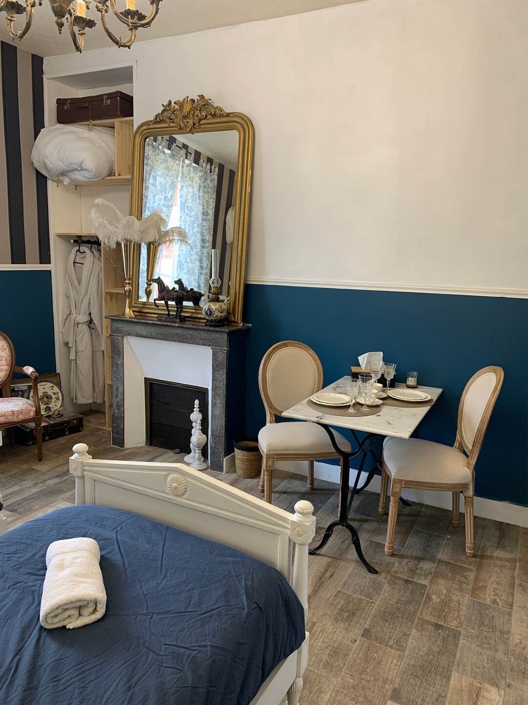 Habitación de hotel con cama, mesa lista para comer, chimenea y espejo con marco decorativo.