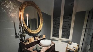 Un bagno con un vanità in legno scuro, un ampio specchio decorativo, un lavabo bianco e una finestra con vista sulla città.