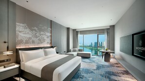 A modern hotel room with a large bed, a seating area, a TV, and a city view. - THE MORDIN HOTEL (Guangzhou)