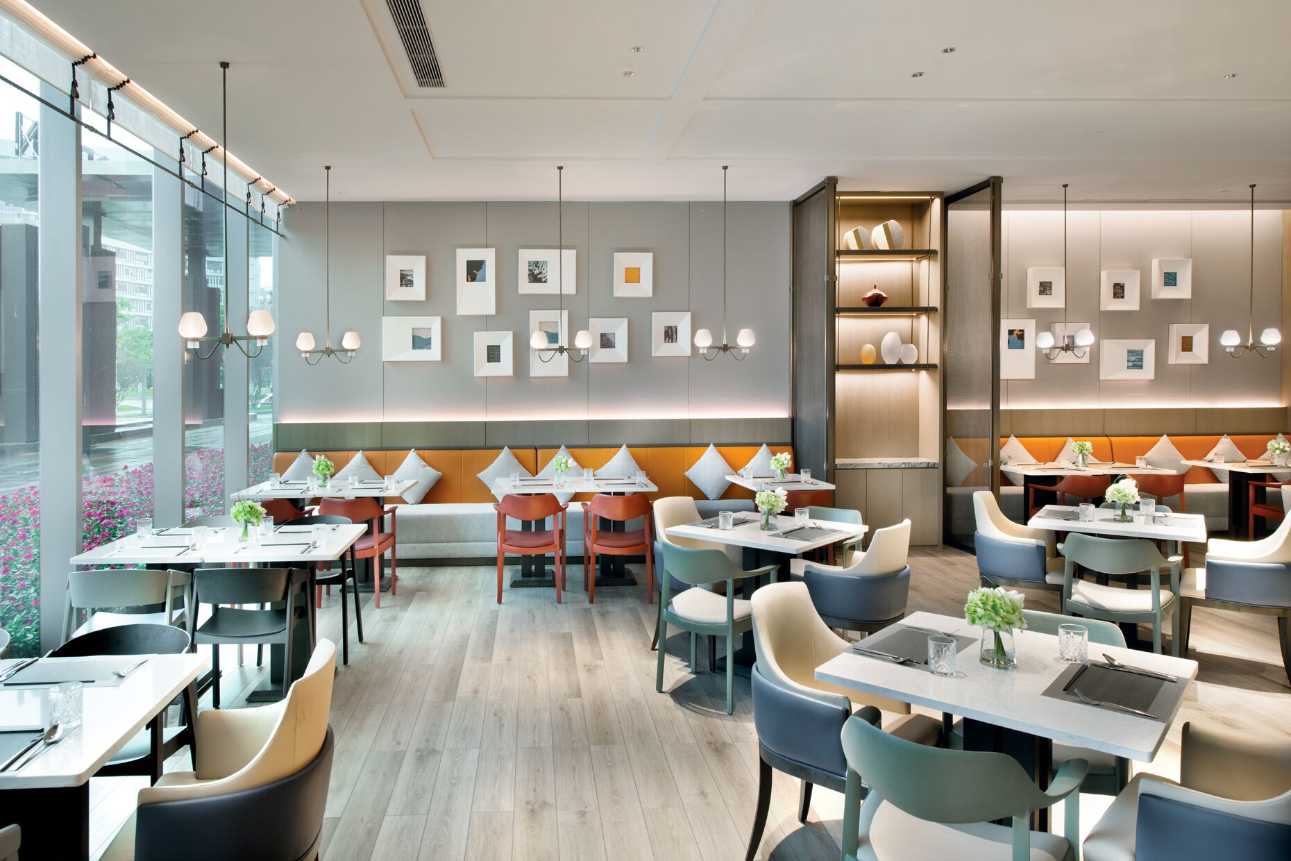 Um restaurante moderno com assentos em boxes e mesas, paleta de cores neutra e obras de arte nas paredes.