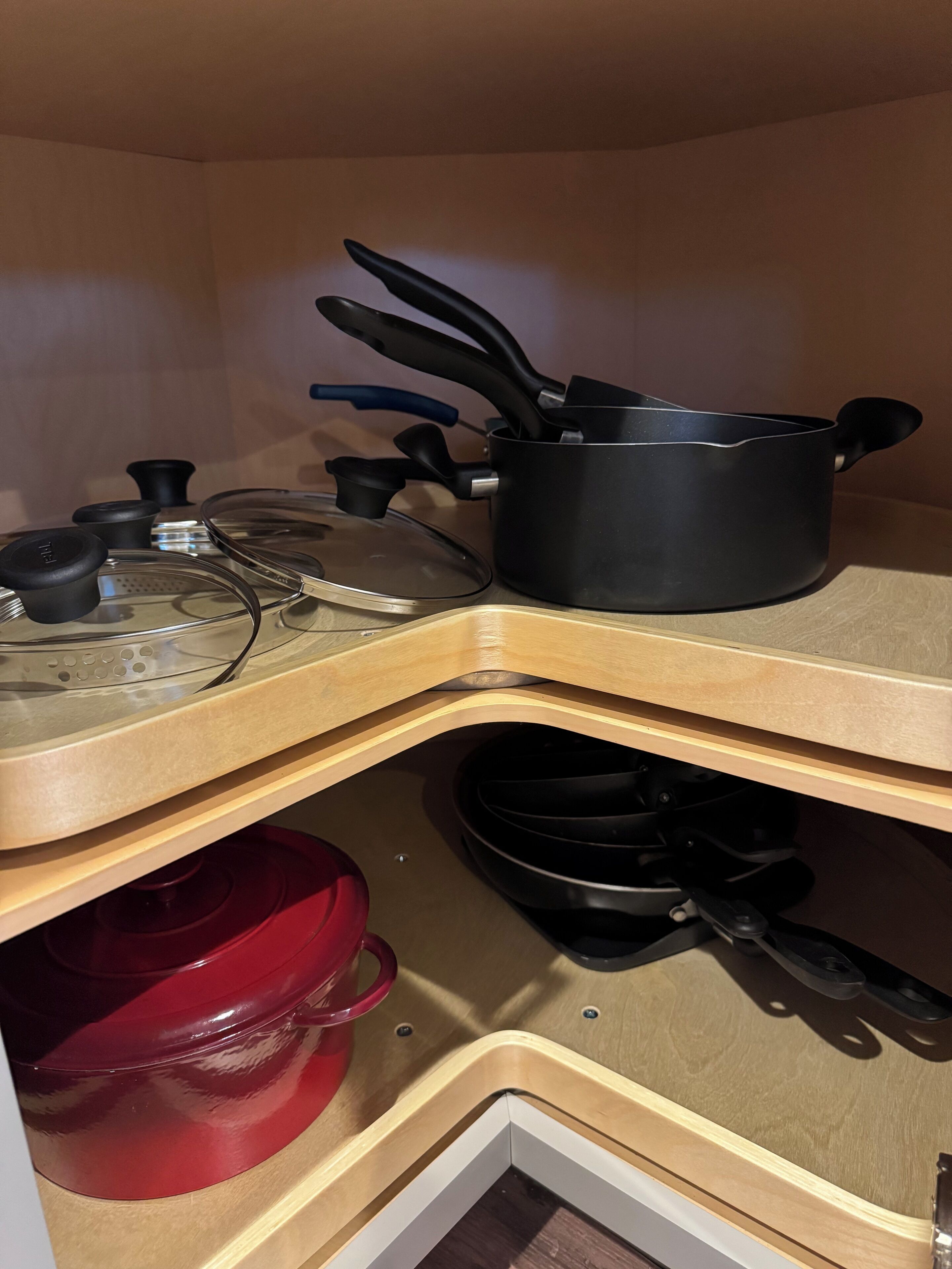 A kitchen with a stove, pots, pans, and a red pot.