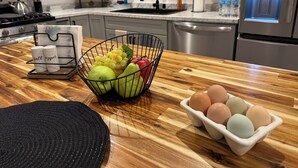 A kitchen with a fruit basket on the counter, salt and pepper shakers, and a carton of eggs.