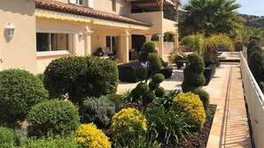 Ein zweistöckiges Haus mit Terrasse, Gartenmöbeln und einem gepflegten Garten.