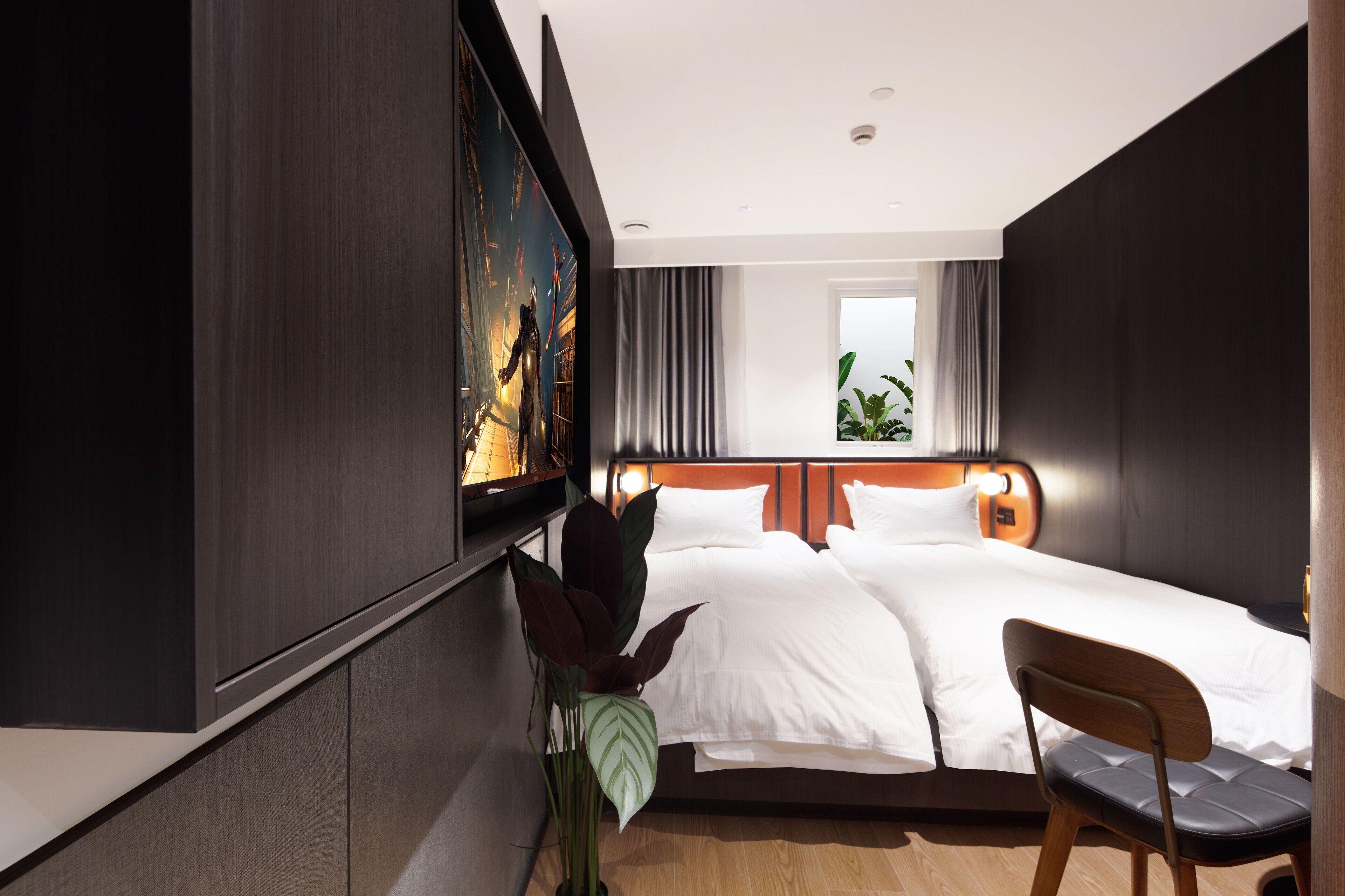 Une chambre d’hôtel avec un lit, une chaise, un grand tableau et une fenêtre avec des rideaux.