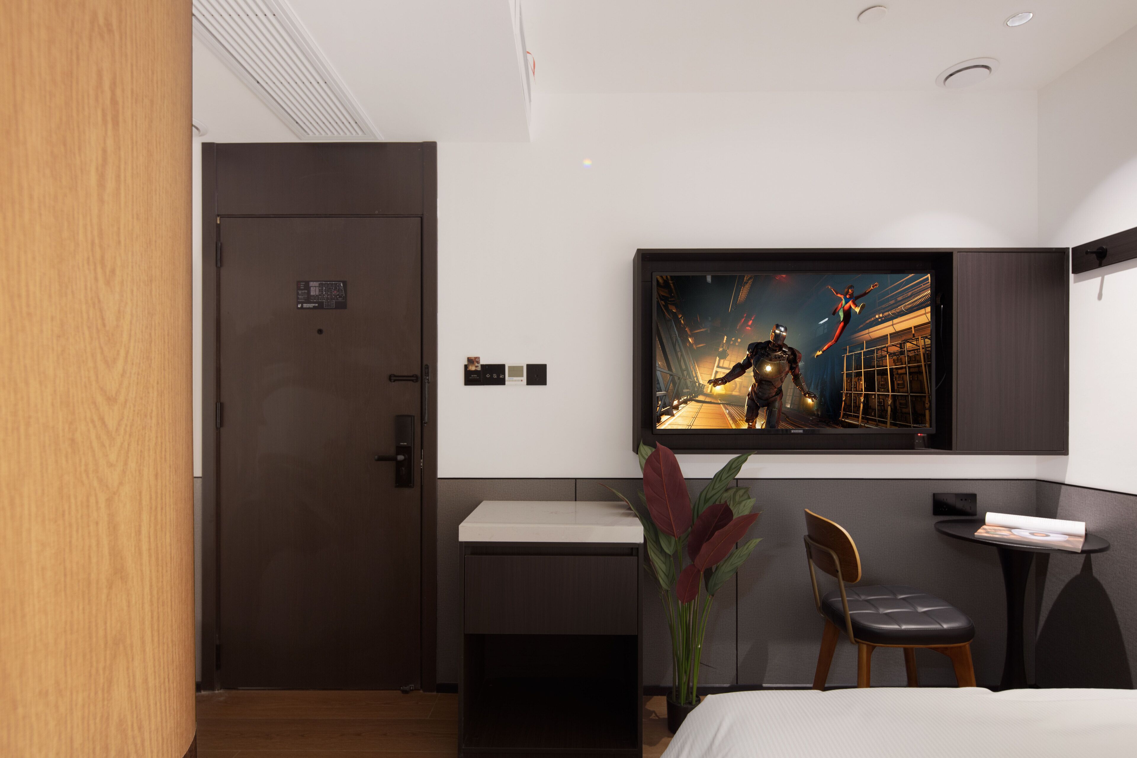 Une chambre d’hôtel moderne avec une porte en bois, un bureau avec une chaise, un lit et un grand tableau encadré au mur.