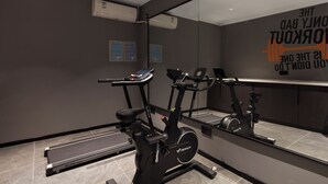 Un gimnasio moderno con bicicletas estáticas, una cinta de correr y un espejo con mensajes motivacionales.