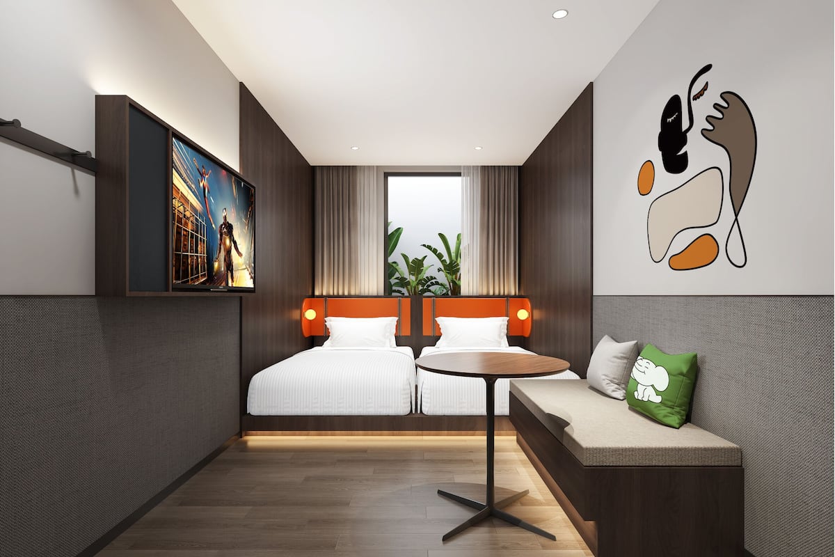 A modern hotel room with a large bed, a sofa, a small table, and a wall-mounted TV.