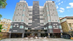 Un bâtiment moderne doté d’une tour centrale, de nombreuses fenêtres et d’une entrée fermée par un portail.