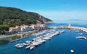 A marina with numerous boats docked, a coastal town with buildings, and a prominent tower on a hill.