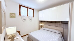 A bedroom with a bed, a nightstand, a lamp, and a window with curtains.