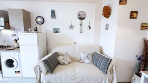 A cozy living room with a sofa, decorative wall art, and a washing machine in the background.