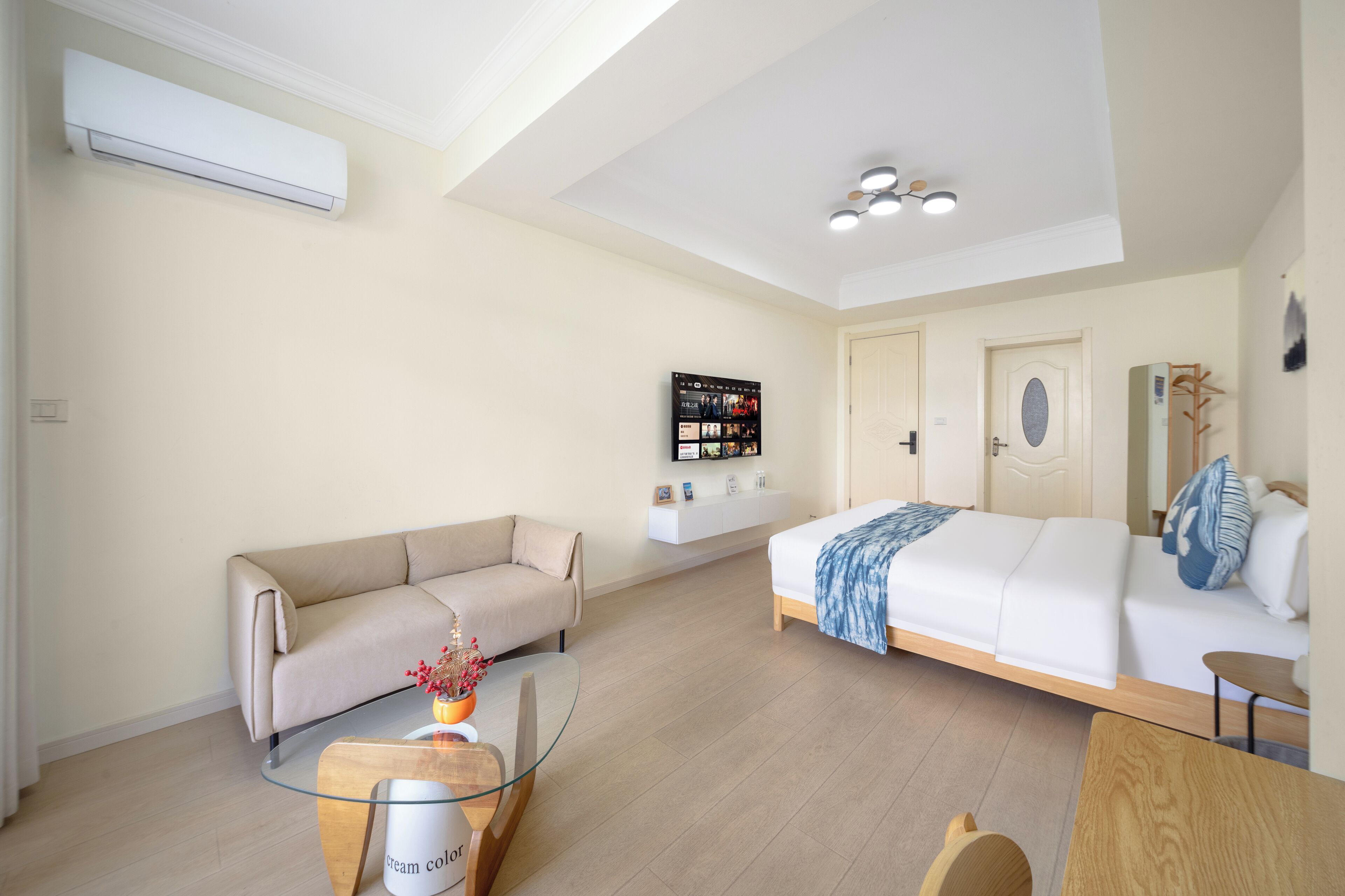 Una camera d'albergo moderna con un divano, un letto, un tavolino in vetro e una TV a parete.