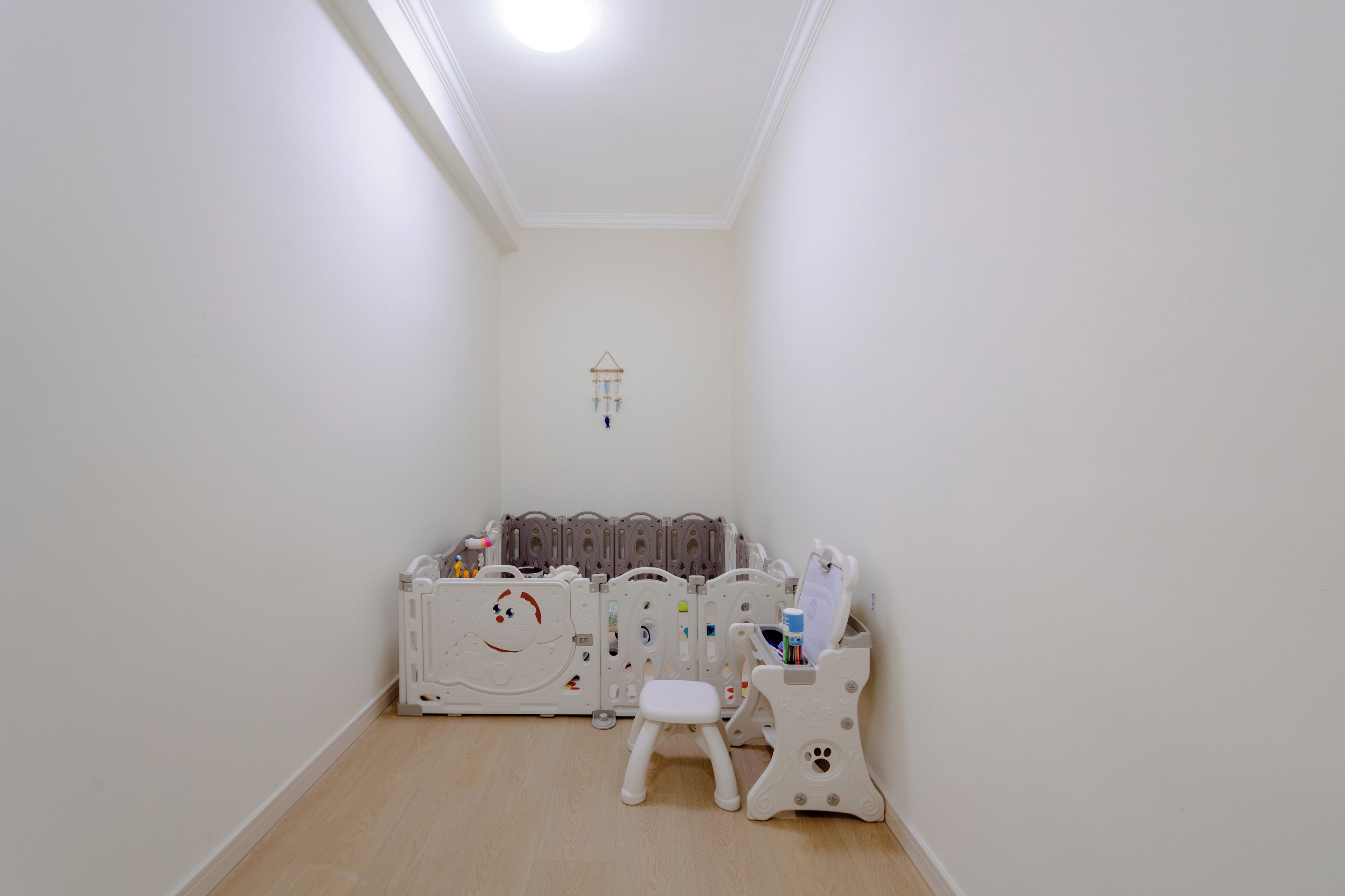 A child’s play area with a playpen, a small stool, and a toy storage unit.